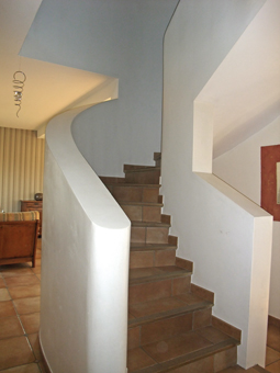 Un escalier en béton, plâtré, carrelé et placé au centre d'une pièce constitue un élément décoratif de la maison